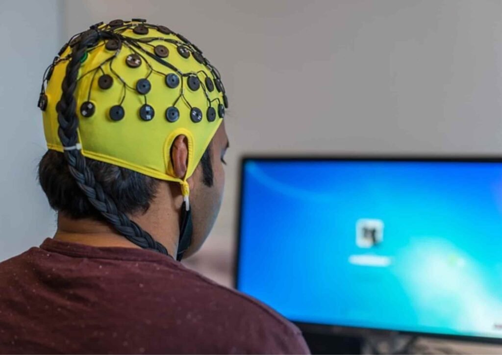 man wearing a neurofeedback device in front of computer at home 