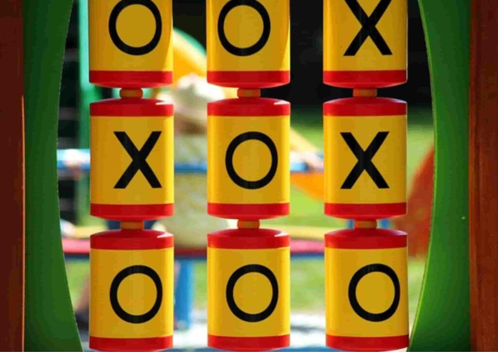A tic-tac-toe game made of rotating cylinders showing X and O symbols on a playground, symbolizing the conclusion or bottom line of an article.