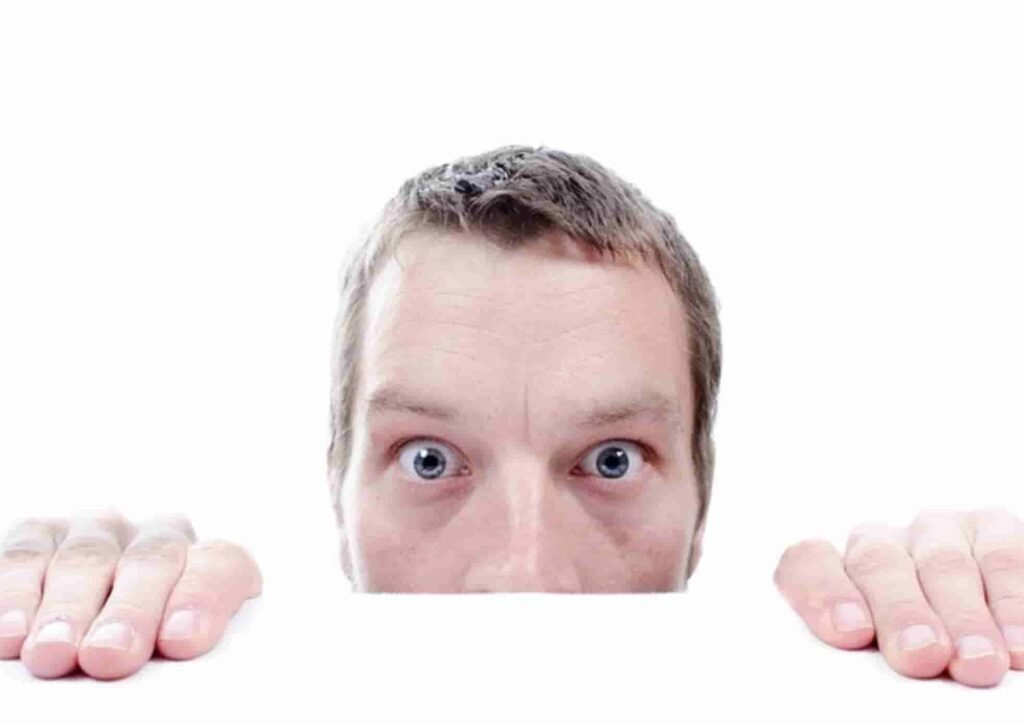 A man peeking over a white surface with wide eyes, symbolizing the ethical privacy concerns of CheatBuster AI